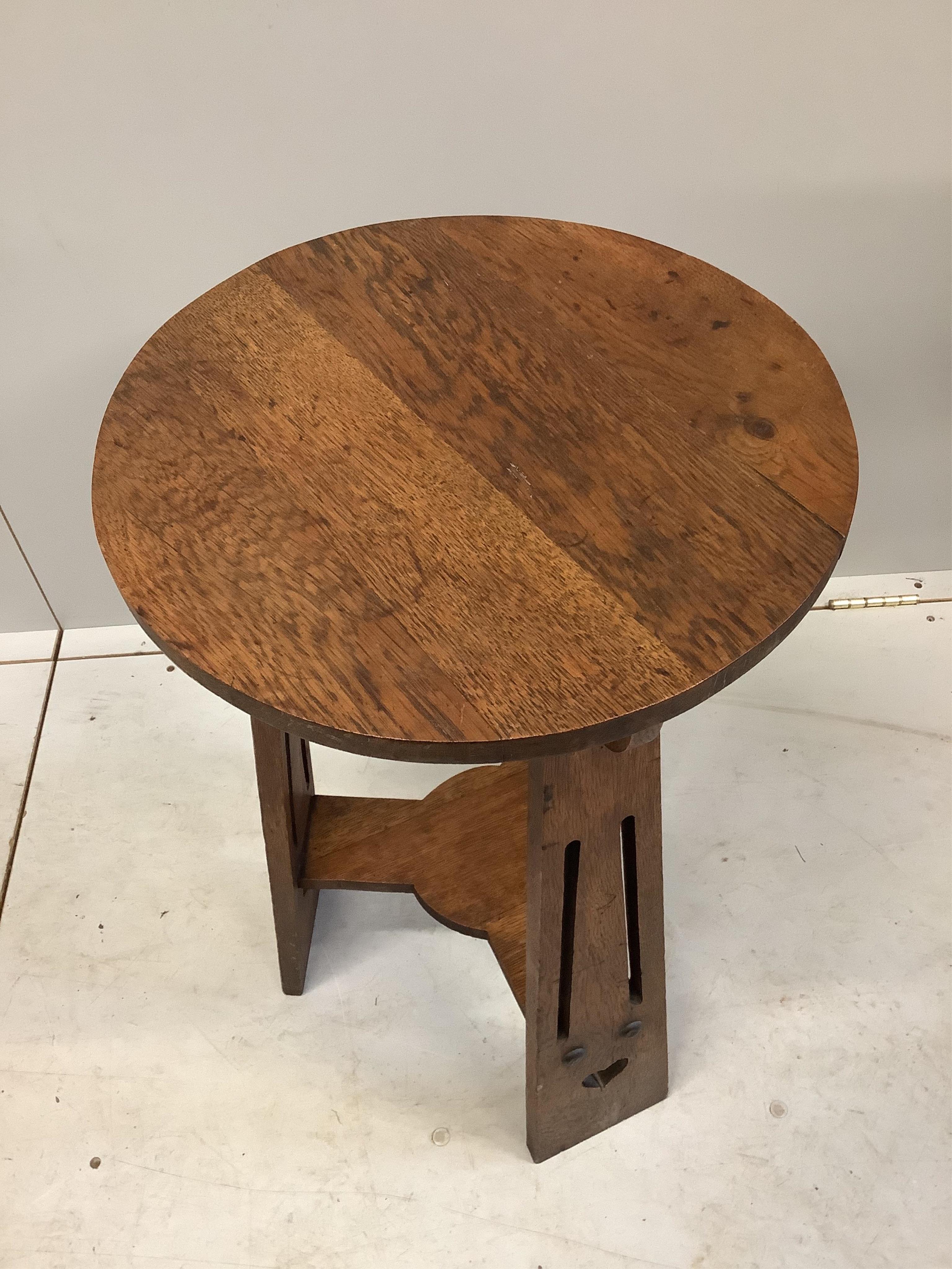 An Arts and Crafts circular oak two tier table, diameter 42cm, height 68cm. Condition - fair